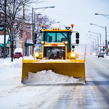 a snow plow moving snow off the road in midwestern town